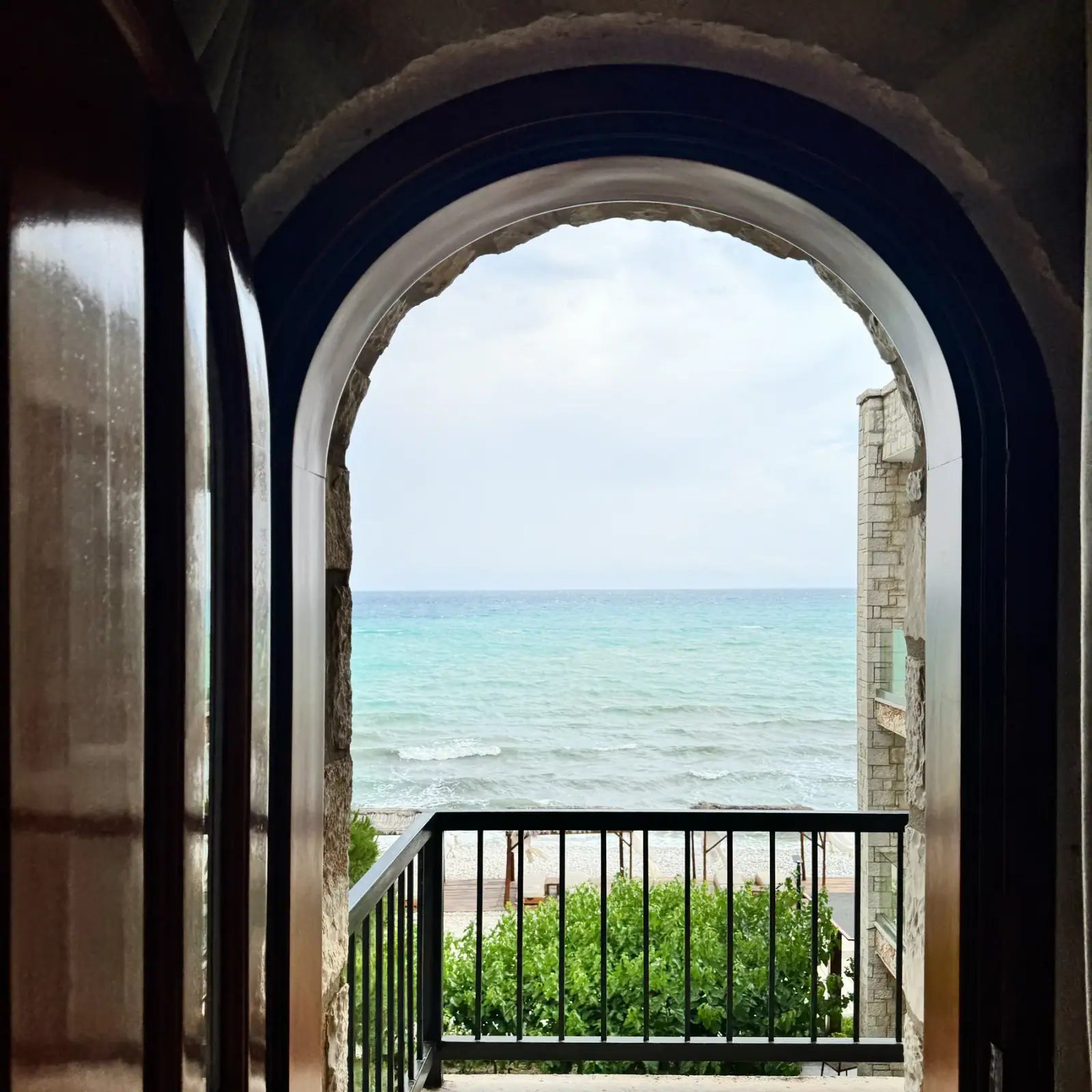 A pointed stone arch opening onto a balcony above the water
