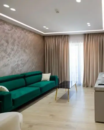The sitting area of a junior suite at Chimaera Hotel with a green velvet sofa, a low table and a polished stucco wall