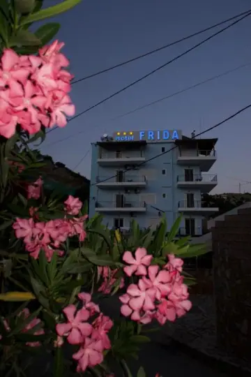 The Hotel Frida roof sign at dusk, above pink oleander