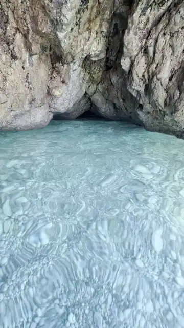 Cave at the water's edge above exceptionally clear shallows