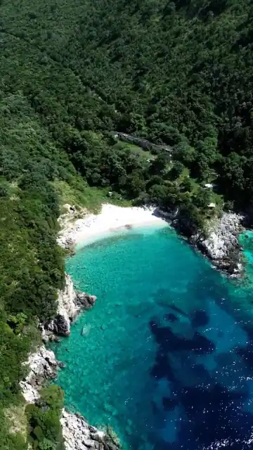 The white crescent of Bear's Bay seen from above, emerald water offshore