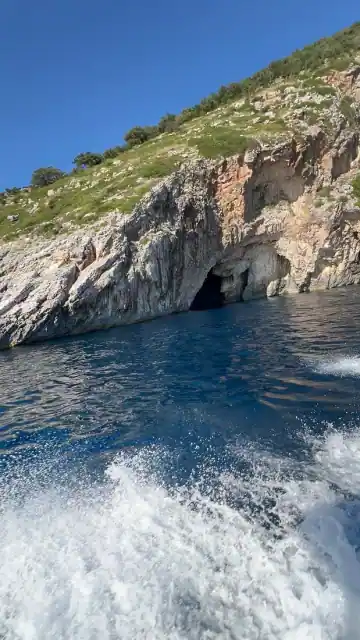 Cliff with several cave openings and surf against the rock