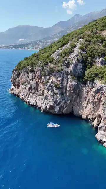 The headland above Pirate's Cave with a boat on deep blue water