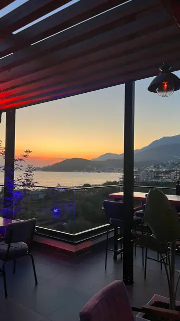 Rooftop Nia Boutique's pergola-covered terrace seating overlooking Himara bay at sunset