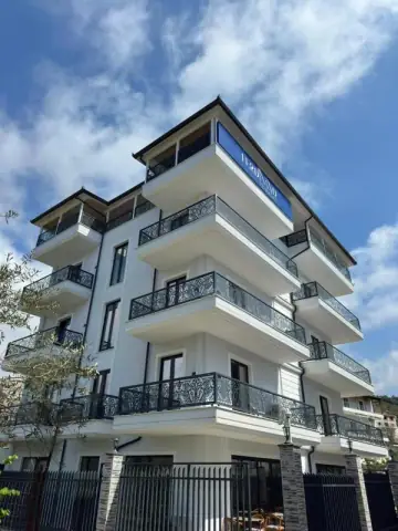 Multi-storey white facade of Ferdinand Residence with balconies in Himara