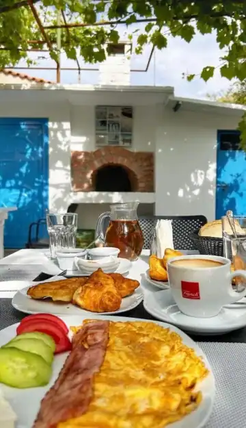 Breakfast laid under the grape vine, facing the whitewashed outbuilding with its brick wood oven and bright blue doors