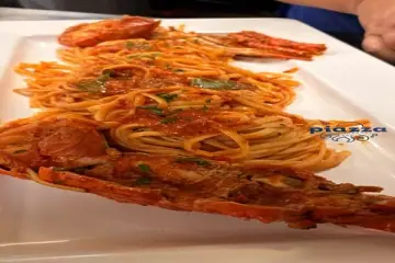 Spaghetti in tomato sauce with shell-on shellfish, served on a long white platter