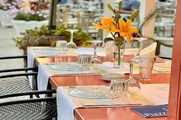 Terrace tables laid with copper-terracotta runners, glassware and orange lilies