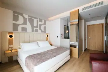 The bed in a Double Room with Sea View, under the printed abstract panel