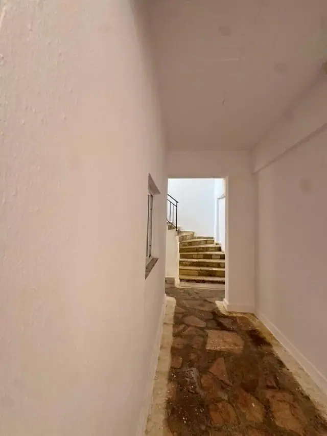 Whitewashed passage with a small window and pale stone steps rising to the upper floor