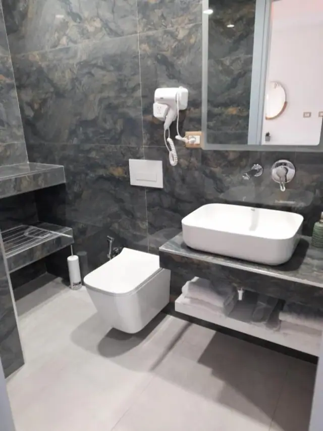 The same stone behind a white basin set on the stone shelf, with towels folded beneath it.