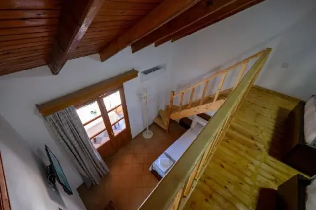 The mezzanine over the stair with a pine handrail and a boarded ceiling above two beds