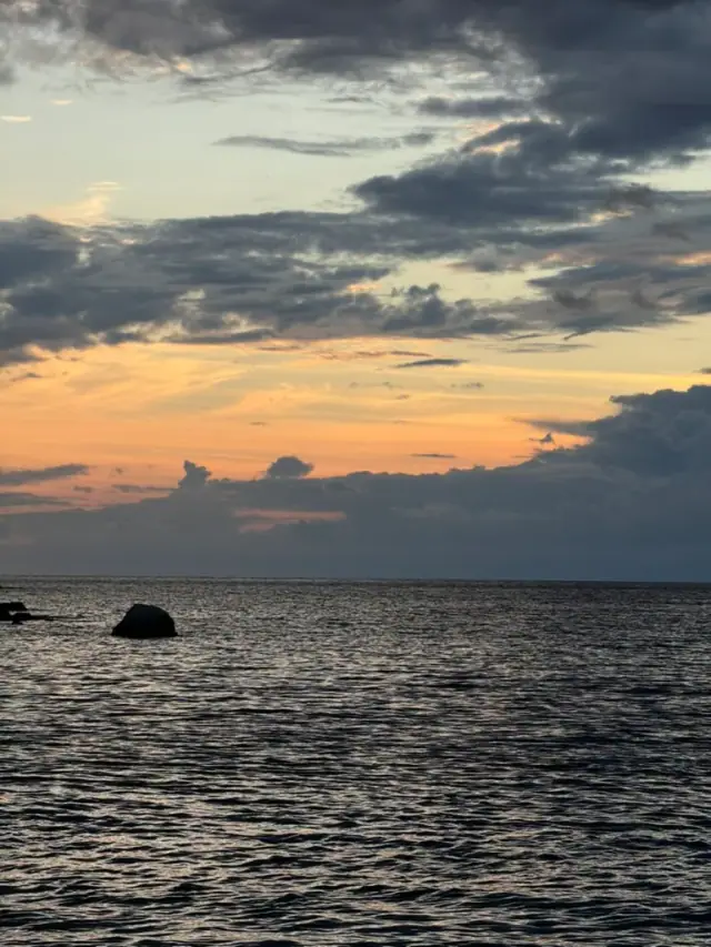 Dusk over the Ionian off Himarë, an amber band under indigo cloud and a rock standing out of dark water