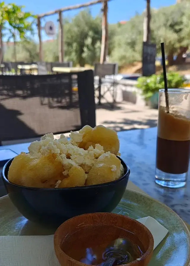 A freddo espresso on a terrace table at Bar 300, beside a bowl of potatoes with feta