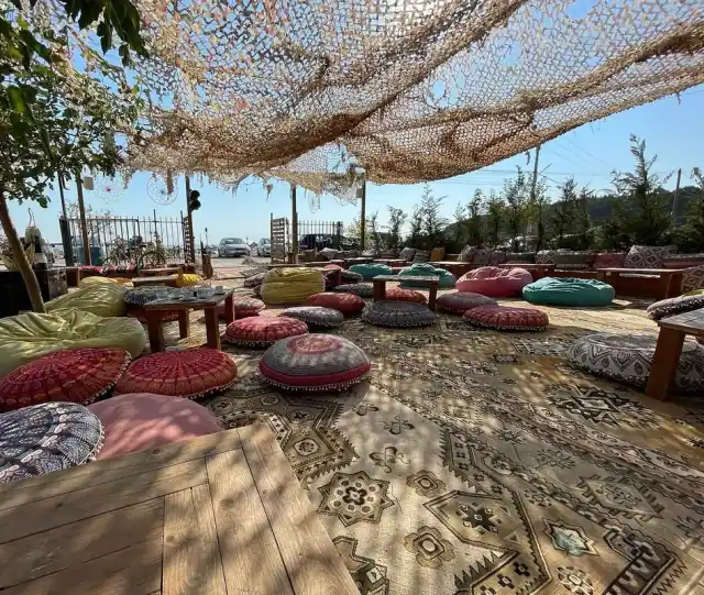 Round mandala floor cushions and bean bags on overlapping kilim rugs under the netting at Boho Livadh