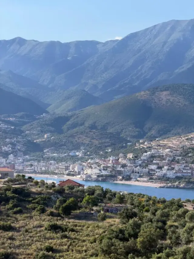 Himarë town on its bay seen from the hillside above, mountains behind