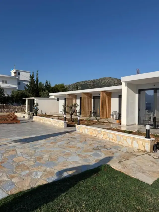 Oak slat screens sliding across the room doors of Filikuri Boutique Hotel, olive trees and flagstone terrace in front
