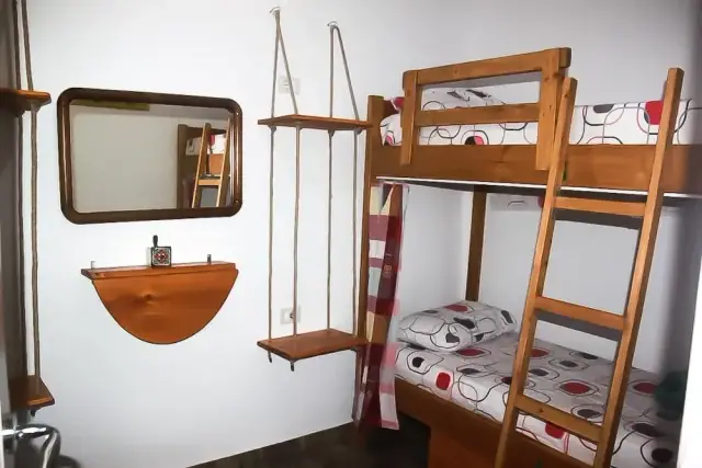 Rope-hung timber shelves and a framed mirror beside a pine bunk bed at Himara Downtown Hostel