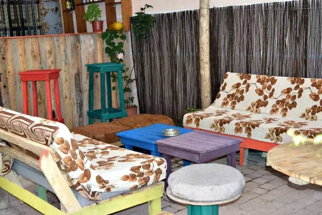 Pallet sofas with floral cushions around a blue and a purple painted pallet table at Himara Downtown Hostel