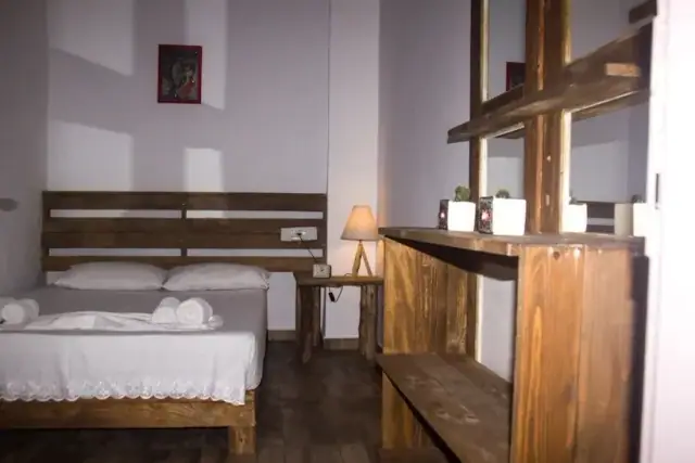 The private double room at Himara Downtown Hostel: a double bed with a plank headboard, folded towels, a bedside lamp and a timber shelf unit