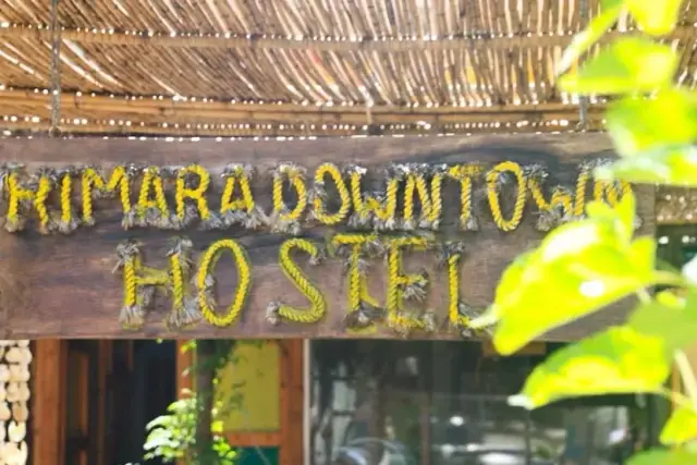 The hostel's sign: the words Himara Downtown Hostel spelled out in yellow rope on a weathered plank under a reed roof