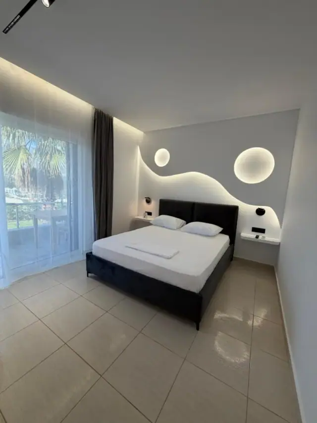 A bed against a sculpted plaster wall that curves like a wave, with two circular lights set into it