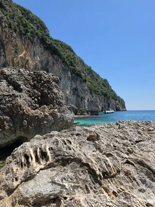 The limestone cliff wall above Alevra's water with a boat beyond
