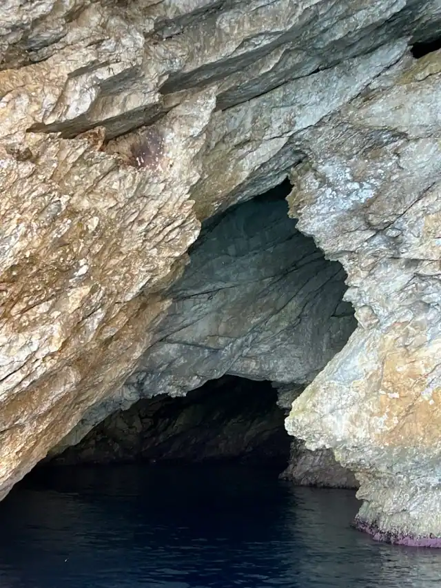 Cave mouth in pale limestone at the waterline