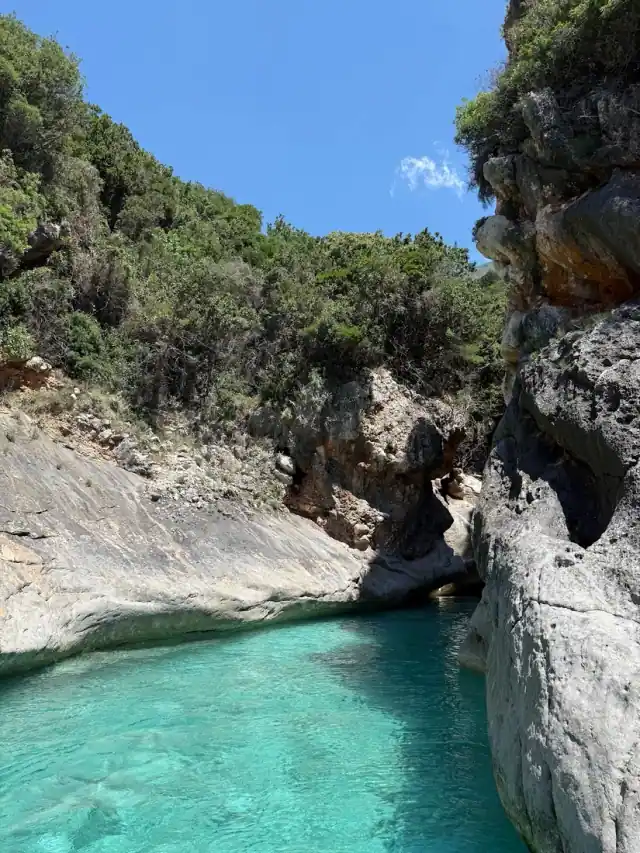 Turquoise water in the narrow limestone inlet of Butterfly Cove on the Albanian Riviera coast