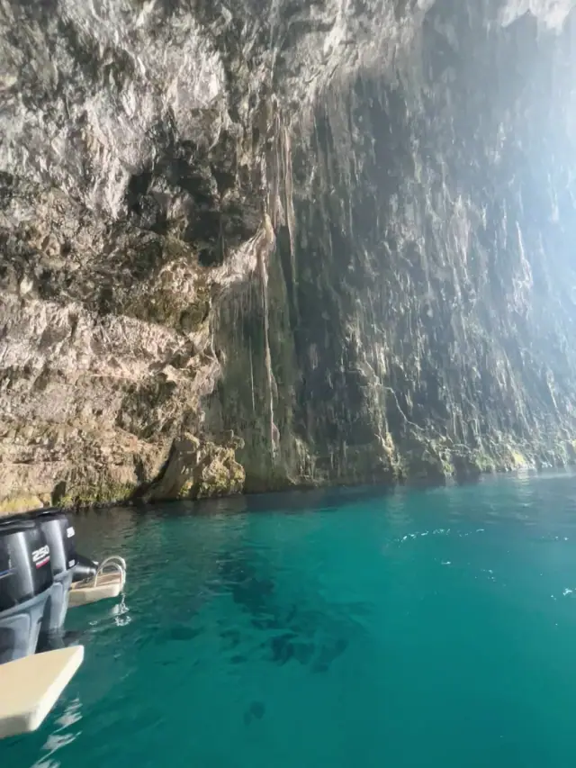 Turquoise water below the cliff wall beside Haxhi Ali Cave