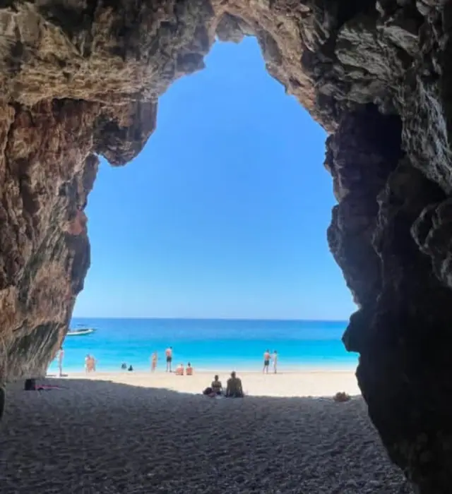 Pigeon's Cave arch framing the turquoise sea and pebble beach beyond