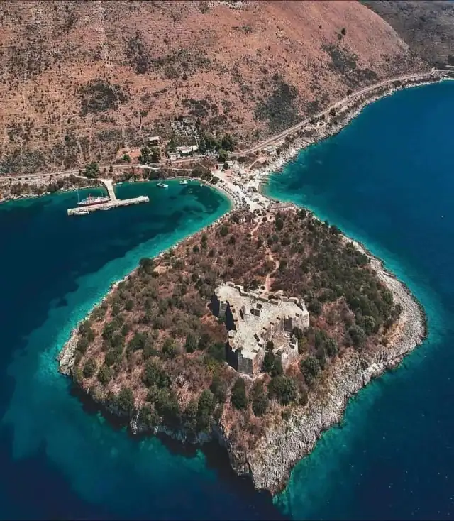 Aerial of the castle peninsula set in the turquoise bay at Porto Palermo