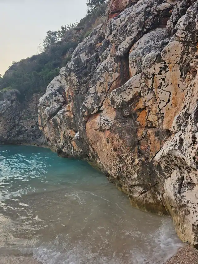 Cliff face dropping to green water at Saint Andrew's Bay