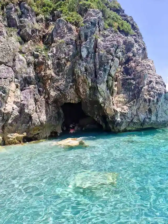 The cave opening in the cliff above turquoise water at Secret Cave