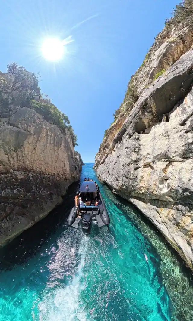 Narrow turquoise water channel between high cliff walls at Smuggler's Canyon on the Karaburun Peninsula