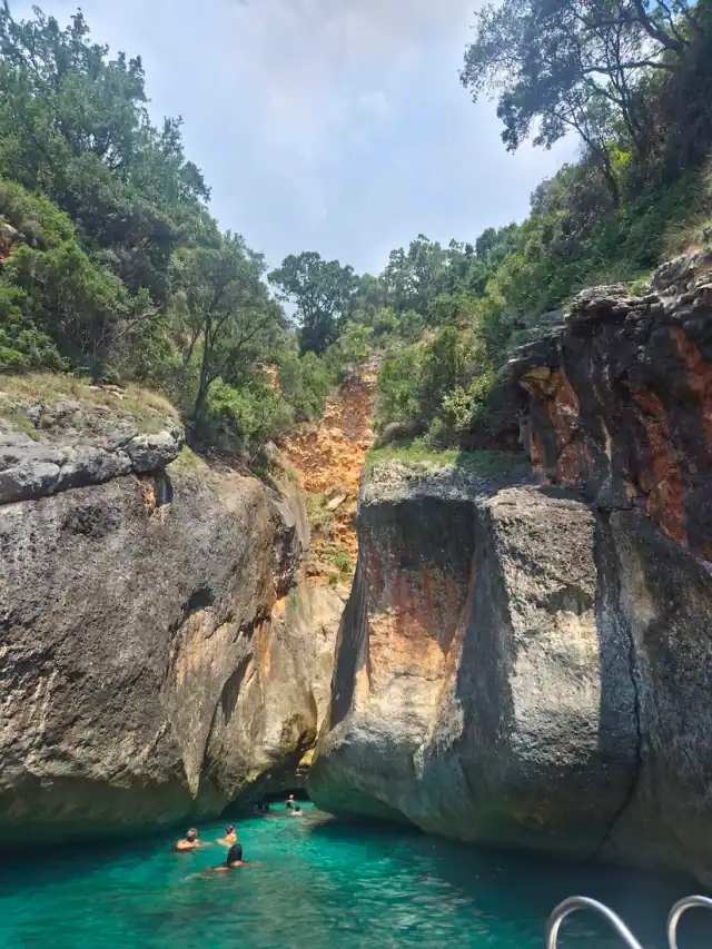 Streaked limestone walls of Thunder Cave rising from the water