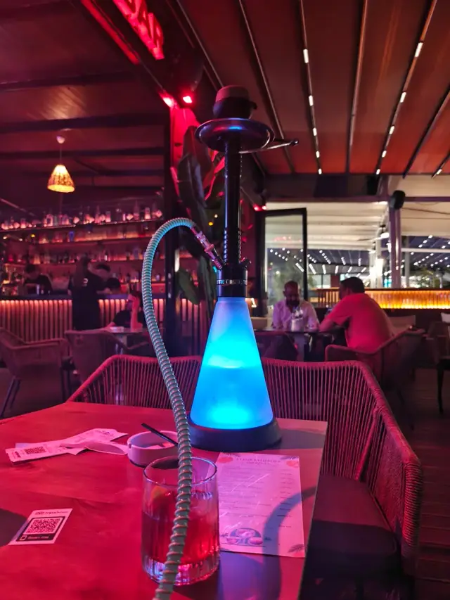Lido Lounge bar interior with shisha, lit drinks shelves and neon bar sign on the Himara seafront
