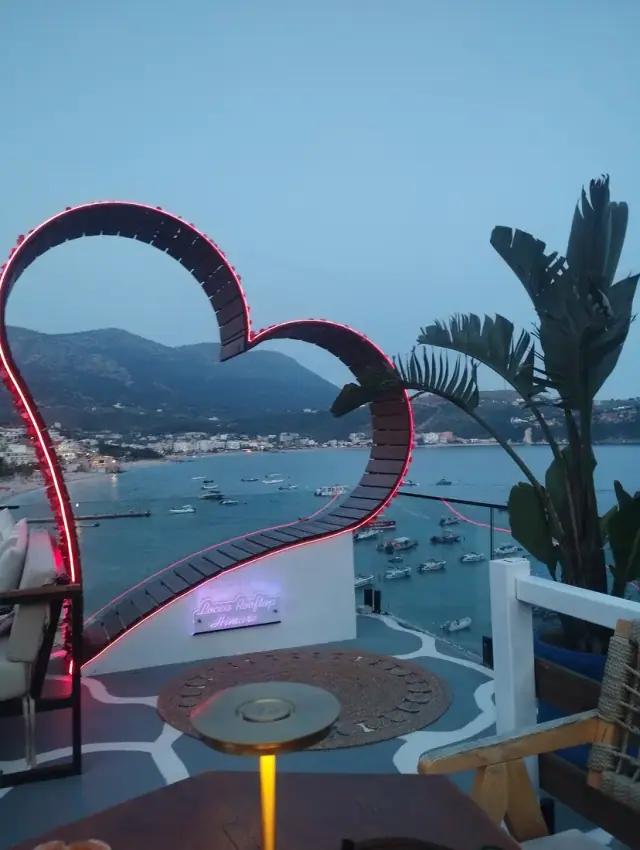 Locca Rooftop terrace with its neon heart sculpture and signage overlooking Himara bay