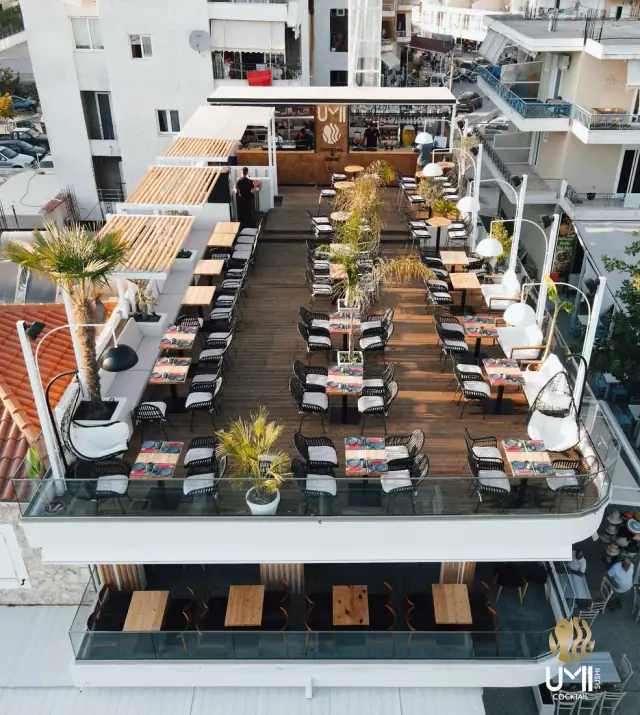 Aerial view of UMI Sushi & Cocktail's rooftop terrace with rows of tables above Himara