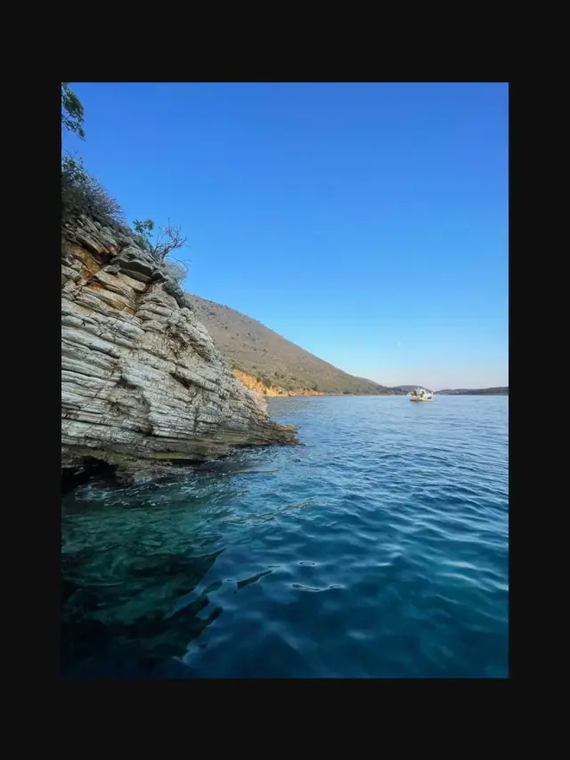 Himara Blue Experience boat on clear turquoise water off the Himara coast, Albanian Riviera