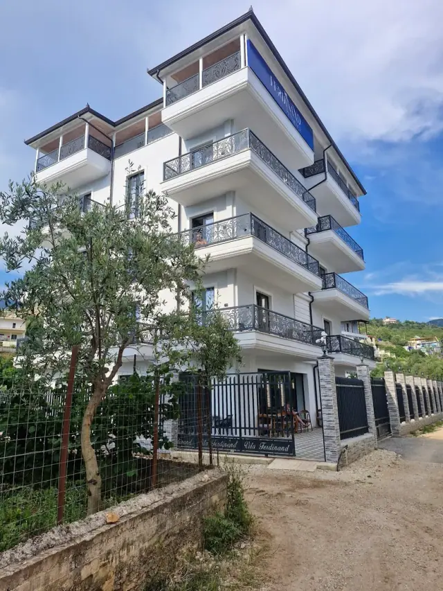 Multi-storey white facade of Ferdinand Residence with balconies in Himara