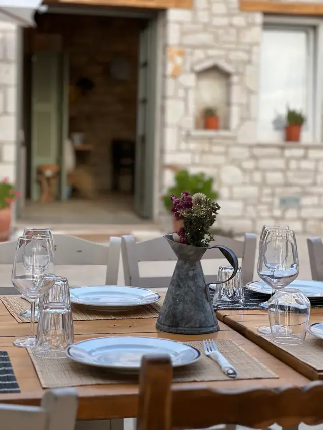 Set outdoor table against a stone wall on the terrace at ELEA Restaurant in Himara