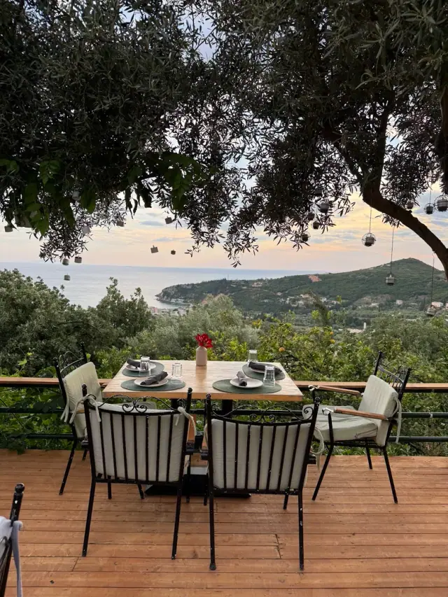 Set table on a wooden deck terrace with hillside and sea view at Fig and Olive Bistro in Himara