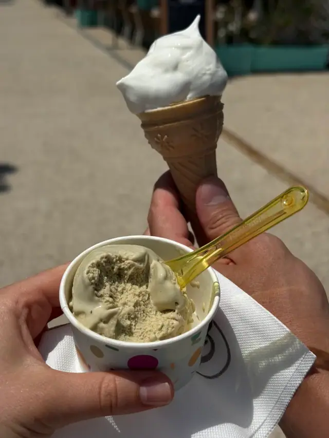 Soft-serve cone and a cup of pistachio gelato held in hand at Iceland Gelato in Himara