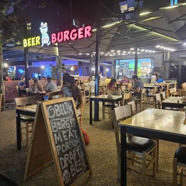 Obelix Beer N Burger outdoor seating and sign at night in Himara