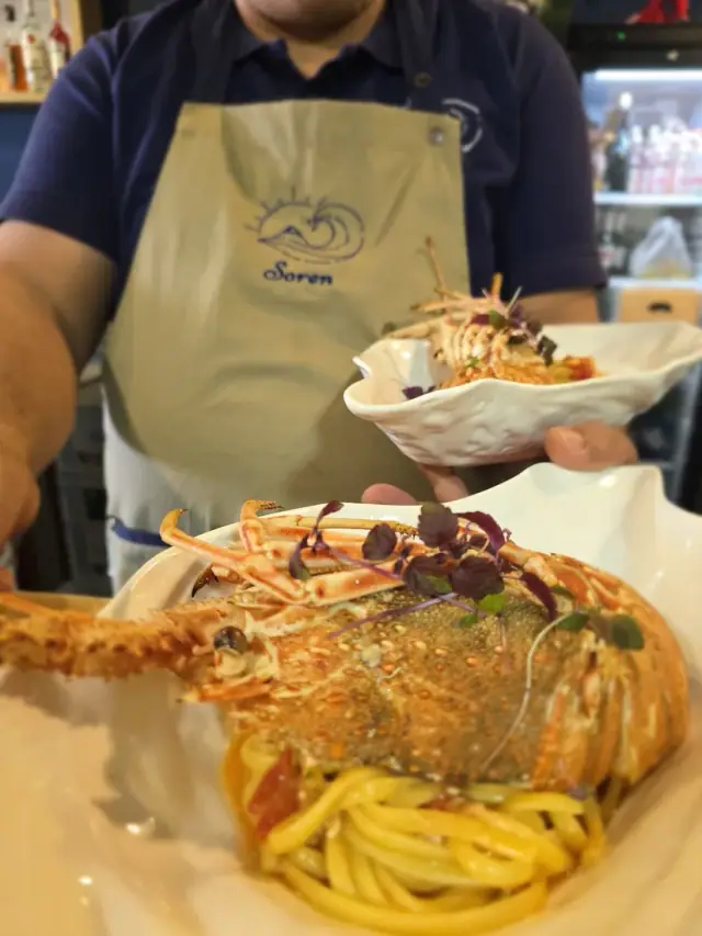 Plated lobster pasta served by staff in a branded Soren apron at Soren Restaurant in Himara