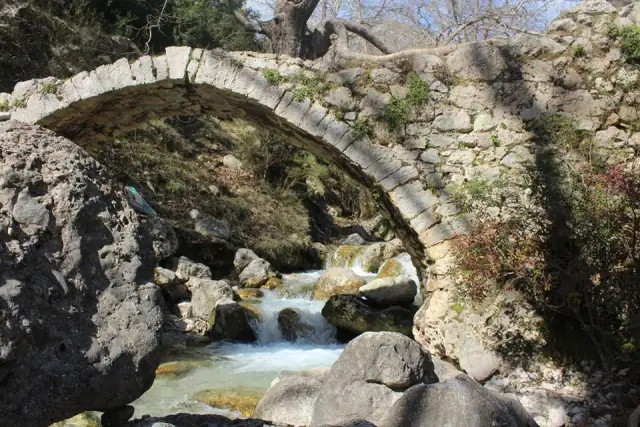 Old arched stone bridge over a rocky stream in the Gjipe Canyon