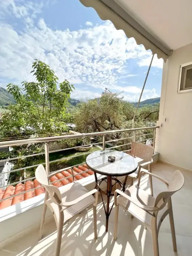 A balcony above the terracotta porch roof looking into the olive grove and up to the mountains