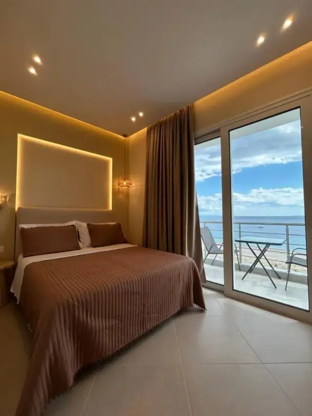 A double room facing the sea, brown ribbed bedspread and a balcony table looking over Livadhi Beach