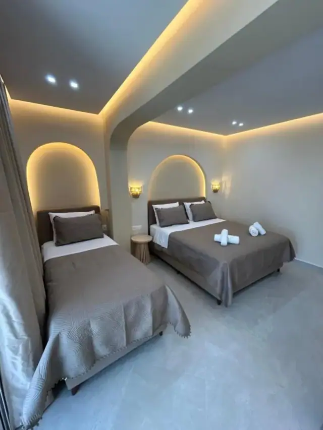 A triple room with two beds, each under its own arc of concealed light